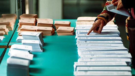 Una persona escogiendo papeleta para las elecciones