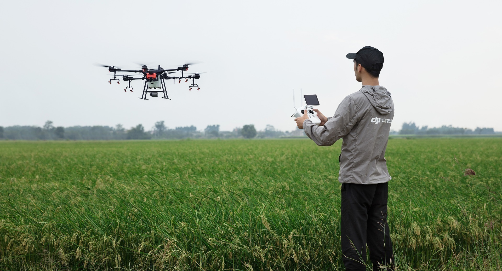Un joven pilota drones en el campo.